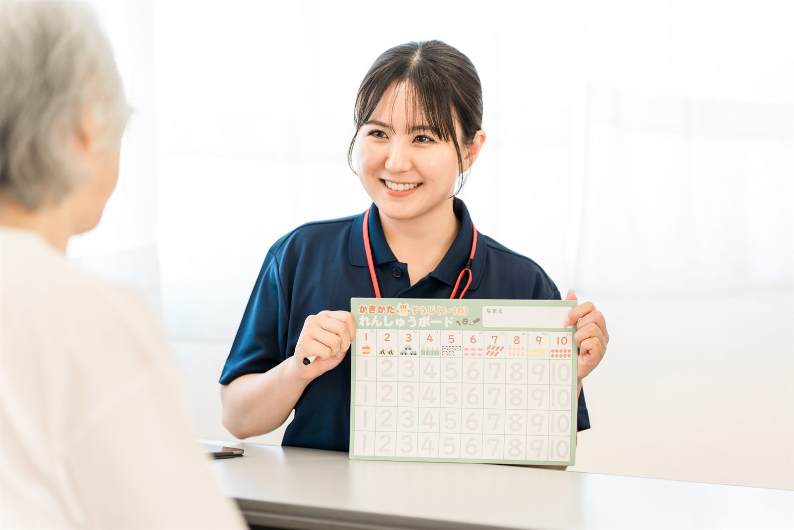 利用者にボードを見せながら説明する介護職員